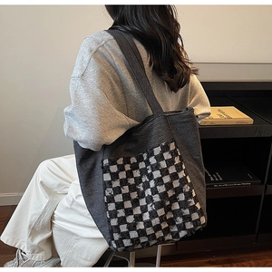 Détail du grand sac cabas en denim gris avec poche en damier et bords effilochés