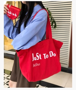 Detail view of large red canvas tote bag and matching zipper pouch with white lettering