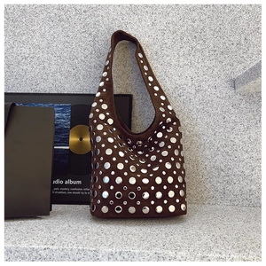 Détail du sac Hobo en daim marron foncé avec des rivets métalliques argentés style punk