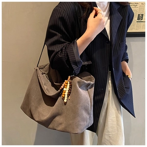 Detail of dark grey retro tote bag with colorful wooden bead tassel and striped blazer
