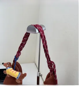 Close-up of brown plush handbag with red-white braided rope handles and dog charm