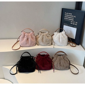 Multiple colors of faux fur drawstring bucket bags with leather handles on display