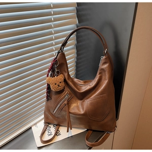 Detail of vintage brown hobo bag with teddy bear charm and side zipper pockets