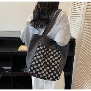 Détail du grand sac cabas en denim avec poche à damier noir et blanc et bords effilochés