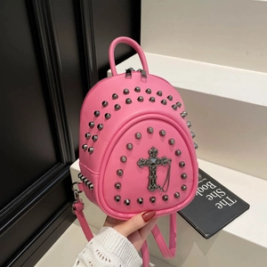 Detailed shot of pink PU leather mini backpack with silver rivets and cross pendant