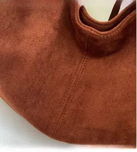 Macro shot of brown suede shoulder bag featuring premium texture and precise double stitching