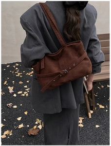 Détail d'un grand cabas en daim marron avec boucles réglables et design rétro minimaliste