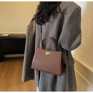 Detail view of retro brown leather handbag with gold twist lock and a stylish trapezoid shape
