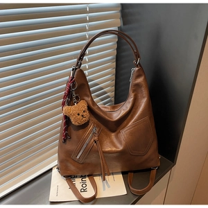 Macro view of brown vintage PU leather backpack with teddy bear charm and woven cord detail