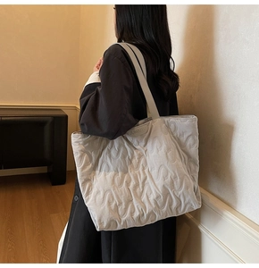 Detailed view of quilted tote bag with S-shaped stitching and long shoulder straps