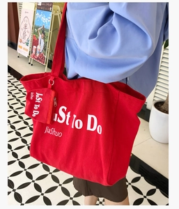 Detail view of a large red canvas tote bag with letter print and matching coin purse
