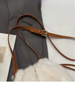 Close-up detail of white plush bucket bag with adjustable brown leather shoulder strap