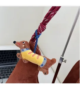 Close-up of brown plush dachshund charm with yellow striped sweater and red woven cord