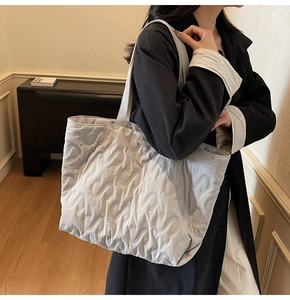 Close-up of light gray quilted tote bag featuring unique S-shaped embossed patterns