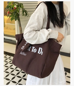 Close-up of brown canvas tote bag with lettering and matching small pouch attachment