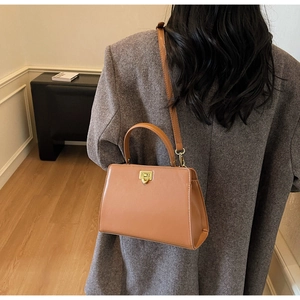 Détail d'un sac à main en cuir marron avec boucle dorée porté en bandoulière