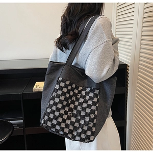 Détail du grand sac cabas en denim gris avec poche à carreaux et bords effilochés