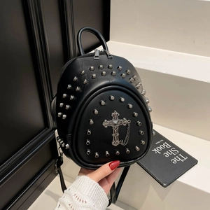 Close-up of a black leather mini backpack with silver rivets and metal cross pendant