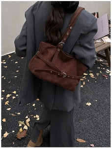 Outdoor shot of dark brown suede shoulder bag with metallic eyelets and strap detail
