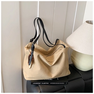 Macro view of large beige tote bag with black leather straps and wood bead charm