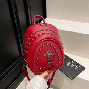 Detail of red punk backpack featuring silver studs, metal cross charm and chain elements