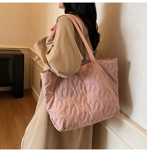 Close-up of pink quilted large tote bag with S-pattern stitching and leather brand tag