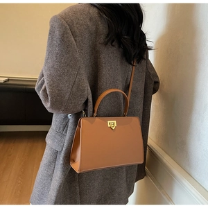 Close-up of caramel brown handbag with golden twist lock and semi-circular handle