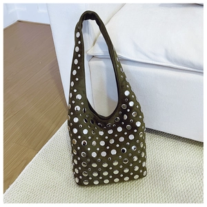 Gros plan du sac seau en daim vert olive avec clous argentés sur un tapis clair