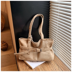 Detail of khaki suede tote bag showing side decorative belt and metal eyelet accents
