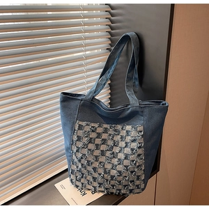 Détail du sac cabas en jean bleu avec patch en damier effiloché et accents de franges