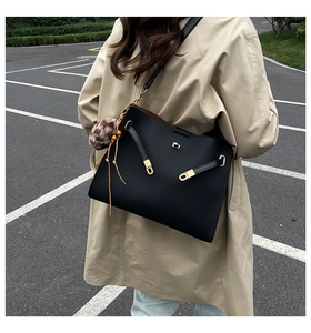 Detail of vintage black leather tote with gold hardware and leopard print pom-pom charm
