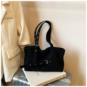 Close-up of minimalist black suede tote bag with metal eyelets and decorative buckles