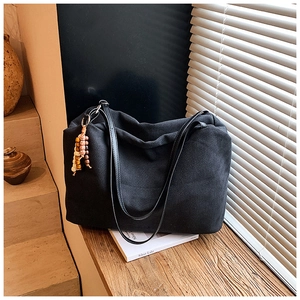 Retro black tote bag featuring a vintage beaded tassel keychain on a wooden window sill