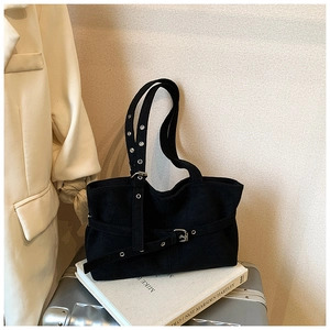 Close-up of black suede tote bag with belt buckle straps and silver metal eyelets details