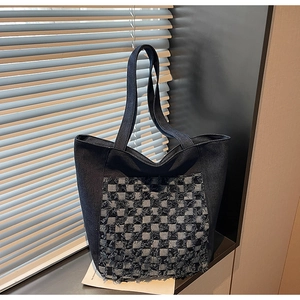 Détail du cabas en denim bleu avec motif à carreaux texturé et finitions à franges uniques