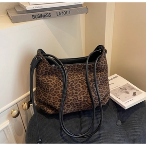Detailed view of leopard print tote bag with thin black straps on a soft blue cushion