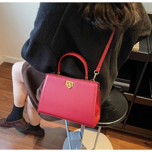 Detail of red leather crossbody bag featuring gold twist lock and slim shoulder strap