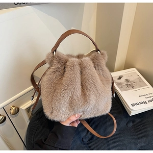 Detail of light brown plush bucket bag showing soft faux fur texture and leather strap