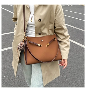 Close-up of caramel faux leather tote bag with gold twist lock and leopard fur charm