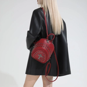 Close-up of red leather mini backpack featuring metal studs and cross pendant detail