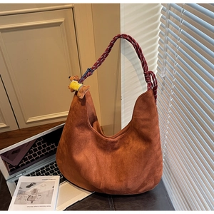 Close-up of brown suede hobo bag with tricolor woven rope handle and dog plush charm
