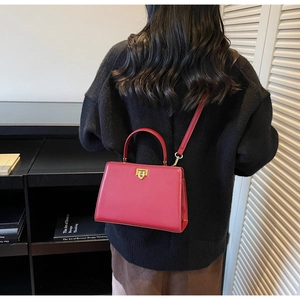 Red structured box bag with gold lock shown on model, detachable strap, luxury style