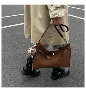 Detail of dark brown leather tote bag featuring a leopard print fur ball charm accessory