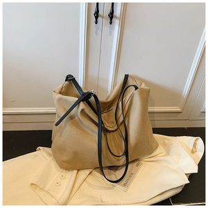 Detail of khaki oversized tote bag featuring black slim straps and adjustable silver buckles