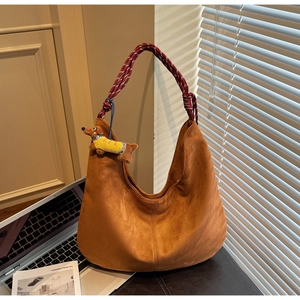 Detail of hobo bag featuring matte brown texture and woven rope shoulder strap
