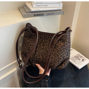 Detailed view of leopard print tote bag with brown handles in a cozy library setting