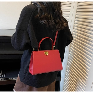 Vue détaillée d'un sac cabas en cuir rouge texturé porté par un mannequin en décor