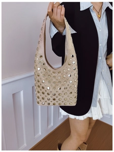 Détail du sac hobo en daim beige avec clous argentés porté par un mannequin