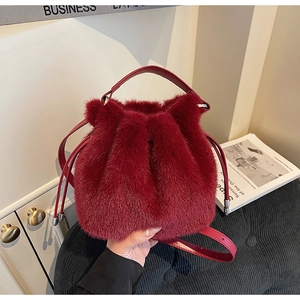 Detail of burgundy faux fur bucket bag with drawstring closure and golden hardware