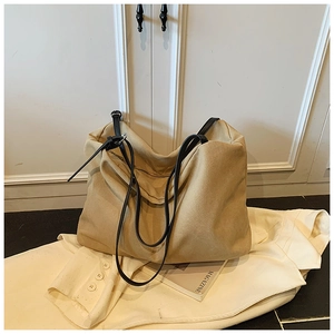Detail of khaki canvas tote bag featuring black slim straps and stylish tie closure